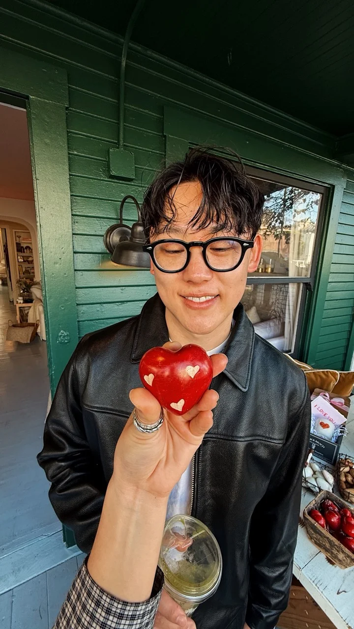 An apple with heart-shaped decorations in front of a smiling face